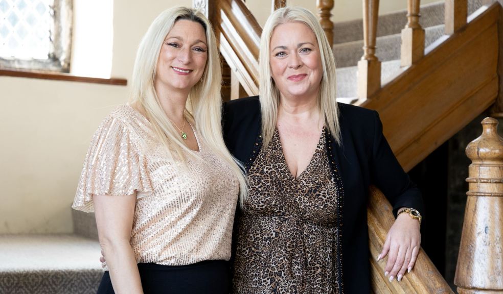 Owners, Cristina Axford (left) and Jo Lines (right) stand on stairs, smiling