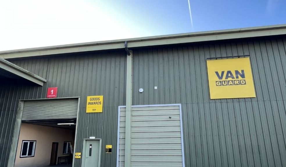 A large industrial warehouse building with green metal siding and a yellow signreading 'VAN GUARD'