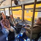 people sat on a bus including a woman in a mobility scooter