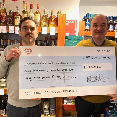 Patrick Agnew (left), Devon Young Carers Service Manager, receives a cheque from Wine World owner Ju